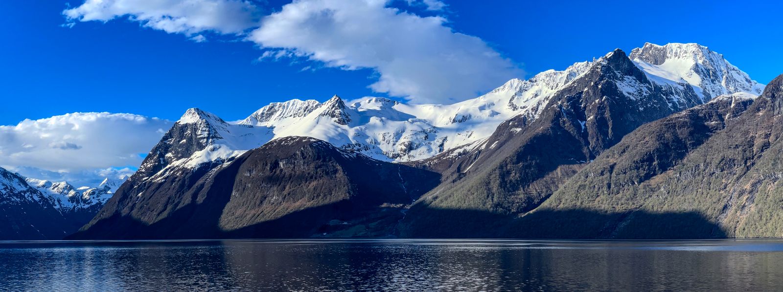 Snow-capped Norwegian mountain peaks reflected in a still fjord
