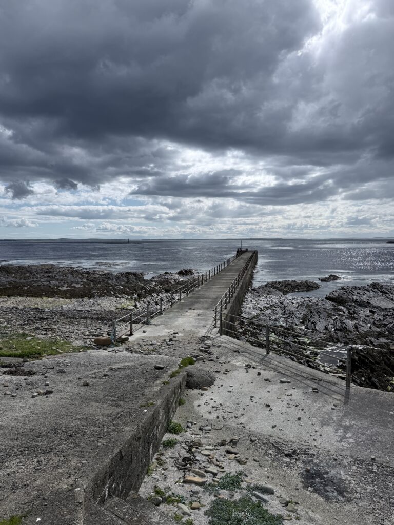 The old causeway and pier by the former ferry port on Orkney's Mainland under a wide grey sky