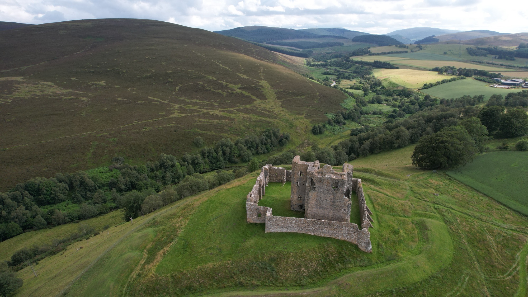 An aerial view of Auchindoun Castle on its green hilltop, ringed by the earthworks of a far older fort.