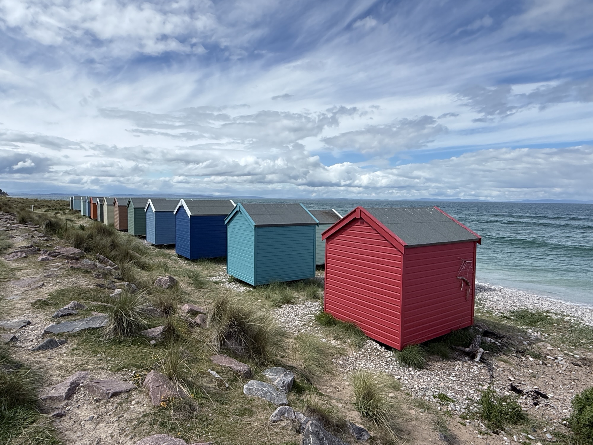 A colourful row of beach huts above the sand at Findhorn Beach on the North Sea, Scotland